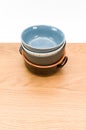 colorful piled up empty stoneware bowls on a wooden tabletop with copy space