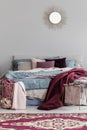 Colorful pillows and burgundy blanket on comfortable bed in fashionable bedroom interior Royalty Free Stock Photo