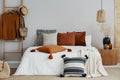 pillows on white bed of classy bedroom with round wooden bedside table and ladder