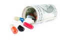 Colorful pills in front of rolled up dollars on white background Royalty Free Stock Photo