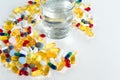 Colorful pills and glass of water, on white background. Royalty Free Stock Photo