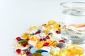 Colorful pills and glass of water, on white background. Royalty Free Stock Photo