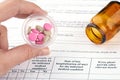 Colorful pills in hand and brown vial with medical questionnaire form on background