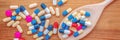 Colorful pills and medication in a wooden cooking spoon, on wood planks panoramic background health and medication concept Royalty Free Stock Photo