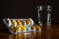 Colorful pills medicine capsule with glass of water on table Royalty Free Stock Photo