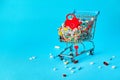 Colorful pills with red heart in shopping cart on blue background. concept: trade in medicines, pharmacies Royalty Free Stock Photo