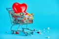 Colorful pills with red heart in shopping cart on blue background. concept: trade in medicines, pharmacies Royalty Free Stock Photo