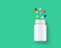 Colorful pills, tablets and capsules spilling out of blank white pill bottle on green background