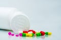Colorful pills on white background and plastic bottle with blank label and copy space. Childproof packaging. Child resistant pill Royalty Free Stock Photo