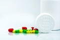 Colorful pills on white background and plastic bottle with blank label and copy space. Childproof packaging. Child resistant pill