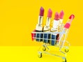 Colorful pink Lipstick in a red shopping cart on orange and yellow background,beauty and shopping concept,selective focus Royalty Free Stock Photo