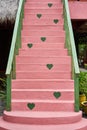 Colorful pink stair with green wooden handrails outdoors