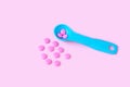 Colorful pink tablets in colored plastic round spoons. Blisters of pills in the background. Concept of medicine Royalty Free Stock Photo