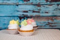 Colorful pink and yellow cupcakes on vintage blue wooden background