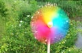 Colorful pinwheel in motion, in front of a green garden