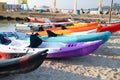 Colorful plactic kayaks or canoe on the beach sand for tourist rent. Surfing boards on stand during summer season Royalty Free Stock Photo