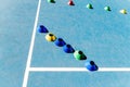 Colorful plastic cones on a blue cement tennis court with white lines background Royalty Free Stock Photo