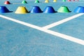 Colorful plastic cones on a blue cement tennis court with white lines background Royalty Free Stock Photo