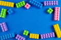 Colorful plastic construction blocks on blue background as kids toys frame Royalty Free Stock Photo