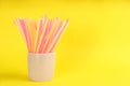 Colorful plastic drinking straws in holder on yellow background, space for text Royalty Free Stock Photo