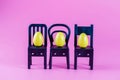 Colorful Plastic Easter Eggs on small chairs on pink background