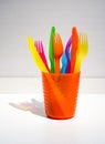 Colorful plastic forks and knives in orange plastic cup Royalty Free Stock Photo