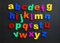 Colorful plastic magnetic letters on black background, top view. Royalty Free Stock Photo