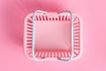 Colorful plastic shopping basket. Empty pink supermarket basket on pink pastel background, top view. Creative minimalist design,