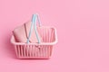 Colorful plastic shopping basket with leather wallet. Empty pink and blue supermarket basket on pink pastel background. Creative