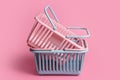 Colorful plastic shopping baskets. Empty pink and blue supermarket baskets on pink pastel background. Creative