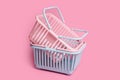 Colorful plastic shopping baskets. Empty pink and blue supermarket baskets on pink pastel background. Creative minimalist design,