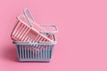 Colorful plastic shopping baskets. Empty pink and blue supermarket baskets on pink pastel background. Creative minimalist design,