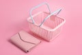 Colorful plastic shopping baskets with leather wallet. Empty pink and blue supermarket basket on pink pastel background