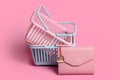 Colorful plastic shopping baskets with leather wallet. Empty pink and blue supermarket baskets on pink pastel background