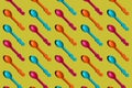 Colorful plastic spoons, pattern on yellow background.