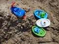 Colorful plastic toy floating boats on sand beach by the ocean