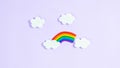 Colorful plasticine rainbow between white paper clouds. Minimalism, copy space. Template for design and text. Light purple Royalty Free Stock Photo