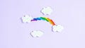 Colorful plasticine rainbow between white paper clouds. Minimalism, copy space. Template for design and text. Light purple Royalty Free Stock Photo