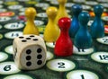 Colorful play figures with dice on black board. copy space Royalty Free Stock Photo