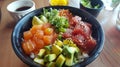 A colorful poke bowl with fresh sashimi, avocado and vegetables. Balanced diet.