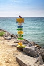 Colorful pole with arrows pointing to place names around the world, on the beach of San Remo
