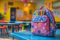 Colorful Polka Dot Backpack with Pencils on Blue Table in Bright Classroom Setting Royalty Free Stock Photo