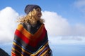 Colorful poncho clothes on happy pretty adult woman enjoying outdoor leisure activity against a blue sky background. Happy and