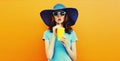 Colorful portrait beautiful young woman drinking a fresh juice wearing a summer hat an orange background Royalty Free Stock Photo