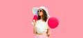 Colorful portrait of beautiful young woman drinking fresh juice with yellow balloon wearing white summer straw hat on blue Royalty Free Stock Photo