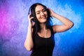 Colorful portrait in blue and pink ligth of a young DJ woman wearing headset and enjoying an electronic music.