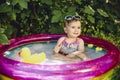 Colorful portrait of cheerful baby enjoying her day in little pool
