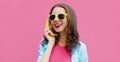 Colorful portrait funny young woman calling on a banana phone on pink background