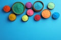 Colorful powders in bowls on light blue background, flat lay with space for text. Holi festival celebration Royalty Free Stock Photo