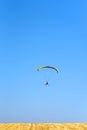 Colorful powered parachute against blue sky and yellow field. Royalty Free Stock Photo